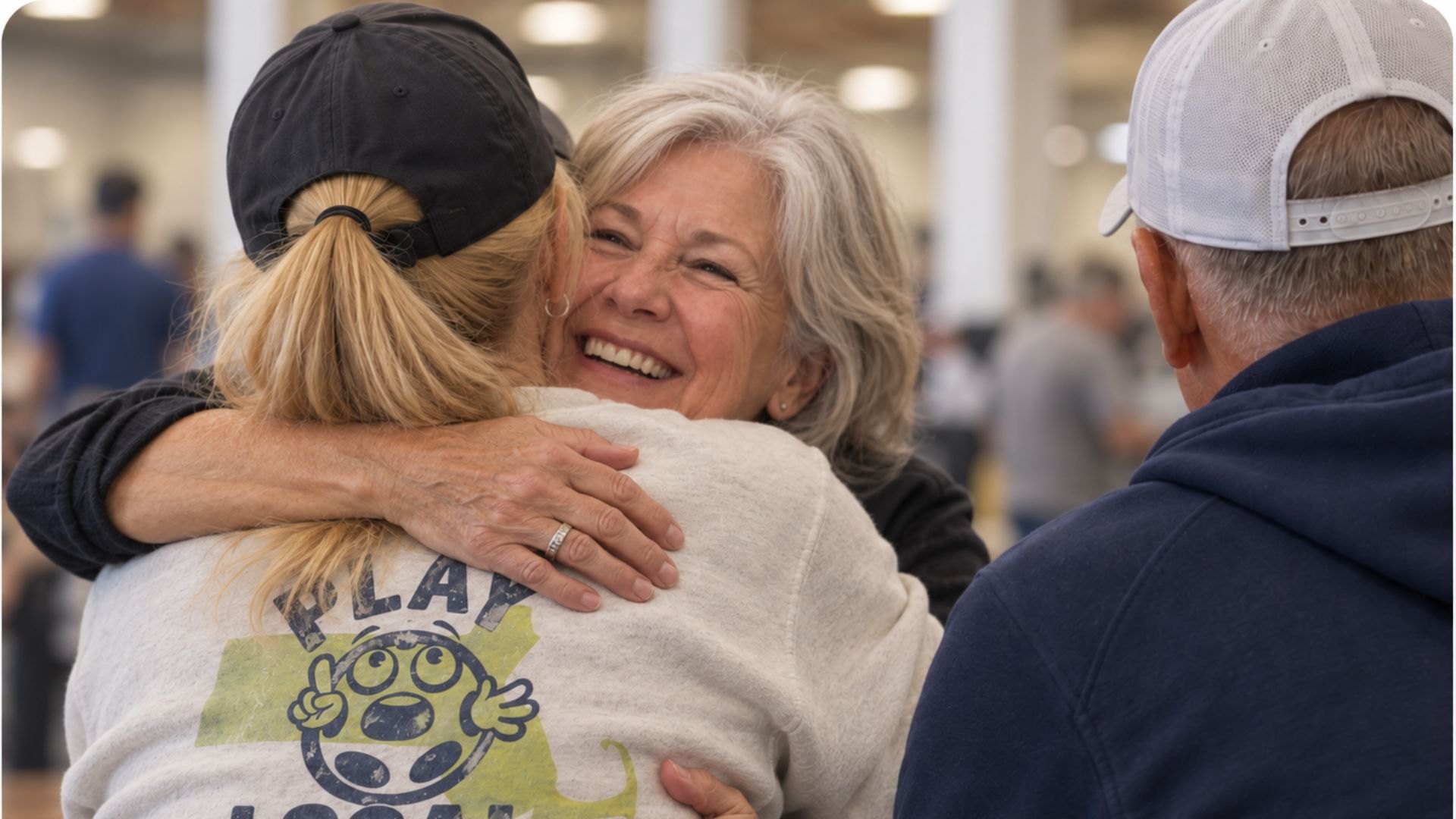 A player smiling mid-hug at a pickleball club